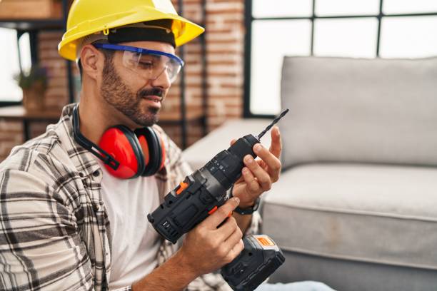 Young hispanic man worker smiling confident holding drill at home