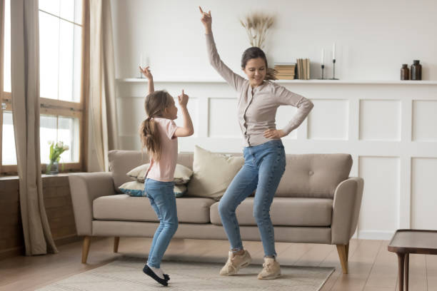Active family young mother dance having fun with little preschool or school age daughter older younger sister listens happy song moving together, leisure activities with kid positive emotions concept
